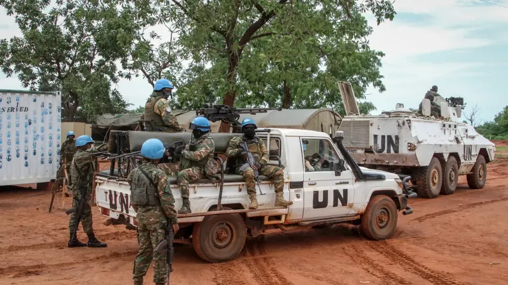 Peacekeepers are seated on a UN vehicle.